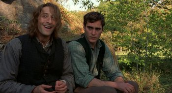 Movie still from “The Village” (2004), directed by M. Night Shyamalan – Two men sitting next to each other on a bench; Medium shot, Low angle