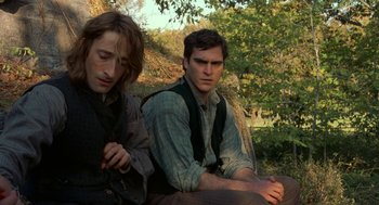 Movie still from “The Village” (2004), directed by M. Night Shyamalan – Two men sitting next to each other on a bench; Medium shot, Low angle