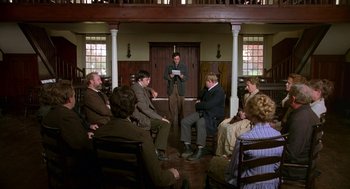 Movie still from “The Village” (2004), directed by M. Night Shyamalan – A group of people sitting in a room; Wide shot, High angle