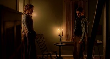 Movie still from “The Village” (2004), directed by M. Night Shyamalan – A man and a woman standing next to lit candles; Medium shot, Low angle