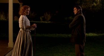 Movie still from “The Village” (2004), directed by M. Night Shyamalan – A man and a woman standing next to each other in a field; Medium shot, Over the shoulder angle