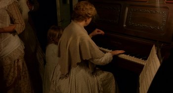 Movie still from “The Village” (2004), directed by M. Night Shyamalan – A woman and a little girl are playing the piano; Medium shot, High angle