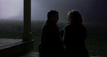 Movie still from “The Village” (2004), directed by M. Night Shyamalan – A man and a woman sitting on a porch at night; Medium shot, Over the shoulder angle