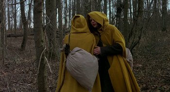 Movie still from “The Village” (2004), directed by M. Night Shyamalan – A couple of people standing next to each other in the woods; Wide shot, High angle