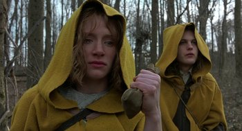 Movie still from “The Village” (2004), directed by M. Night Shyamalan – A woman in a yellow hooded jacket holding a wooden stick; Close Up shot, Low angle