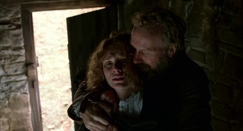 Movie still from “The Village” (2004), directed by M. Night Shyamalan – A man and a woman embracing each other in a dark room; Close Up shot, Low angle