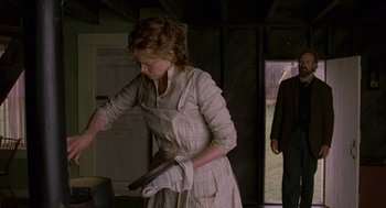 Movie still from “The Village” (2004), directed by M. Night Shyamalan – A woman in an apron is holding a pan; Medium shot, Low angle