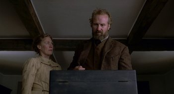 Movie still from “The Village” (2004), directed by M. Night Shyamalan – A man standing next to a woman in front of a wooden box; Medium shot, Low angle