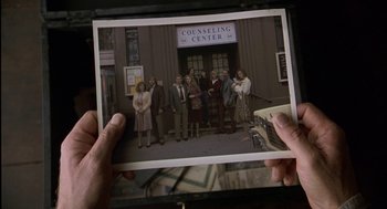 Movie still from “The Village” (2004), directed by M. Night Shyamalan – A person holding an old photo of a group of people; Wide shot, High angle