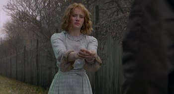 Movie still from “The Village” (2004), directed by M. Night Shyamalan – A woman in a dress is holding her hands out; Medium shot, Over the shoulder angle