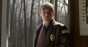 Movie still from “The Village” (2004), directed by M. Night Shyamalan – A man in a brown jacket and a cap; Close Up shot, Low angle