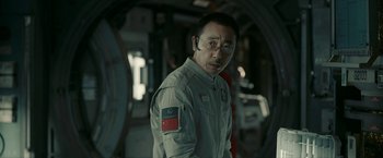 Movie still from “The Wandering Earth II” (2023), directed by Frant Gwo – A man in a gray suit is looking at the camera; Close Up shot, Over the shoulder angle