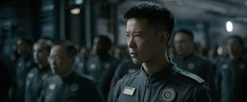 Movie still from “The Wandering Earth II” (2023), directed by Frant Gwo – A man with a badge on his chest looks at the camera; Close Up shot, Over the shoulder angle