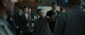 Movie still from “The Wandering Earth II” (2023), directed by Frant Gwo – An older man in a gray suit points to something on the ground; Medium shot, Over the shoulder angle