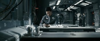 Movie still from “The Wandering Earth II” (2023), directed by Frant Gwo – A man sitting at a table looking at a phone; Medium shot, Low angle