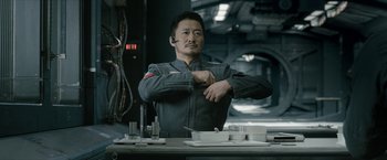 Movie still from “The Wandering Earth II” (2023), directed by Frant Gwo – A man in a grey uniform sitting in front of a table; Medium shot, Low angle