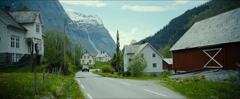 Movie still from “The Wave” (2015), directed by Roar Uthaug – A car driving down a road next to some houses; Extreme Wide shot, High angle