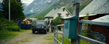 Movie still from “The Wave” (2015), directed by Roar Uthaug – A man walking down the street in front of a house; Extreme Wide shot, High angle