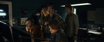 Movie still from “The Wave” (2015), directed by Roar Uthaug – A group of people standing in a room; Medium shot, Over the shoulder angle
