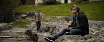 Movie still from “The Wave” (2015), directed by Roar Uthaug – Two young men are sitting on a rocky cliff; Wide shot, Over the shoulder angle