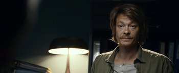 Movie still from “The Wave” (2015), directed by Roar Uthaug – A man standing in front of a lamp in a dark room; Close Up shot, Over the shoulder angle