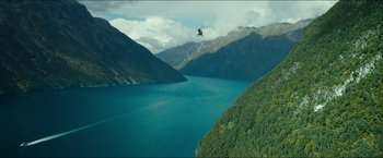 Movie still from “The Wave” (2015), directed by Roar Uthaug – A helicopter flying over a body of water near mountains; Extreme Wide shot, High angle