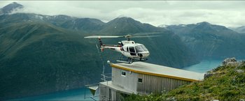 Movie still from “The Wave” (2015), directed by Roar Uthaug – A helicopter is flying over a building on the side of a mountain; Extreme Wide shot, High angle