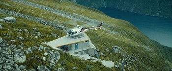 Movie still from “The Wave” (2015), directed by Roar Uthaug – A helicopter is flying over a building on the side of a mountain; Extreme Wide shot, High angle