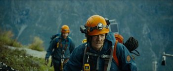 Movie still from “The Wave” (2015), directed by Roar Uthaug – A man in a helmet is walking in the woods; Medium shot, Low angle