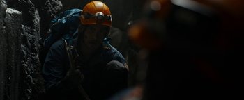 Movie still from “The Wave” (2015), directed by Roar Uthaug – A man with a helmet and a backpack on; Medium shot, Over the shoulder angle