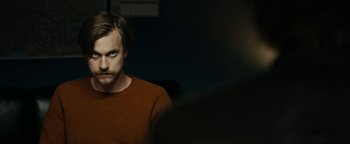 Movie still from “The Wave” (2015), directed by Roar Uthaug – A man in a red shirt is sitting in front of a camera; Close Up shot, Over the shoulder angle