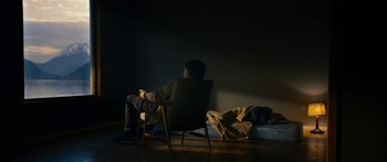 Movie still from “The Wave” (2015), directed by Roar Uthaug – A man sitting in a chair in a dark room; Wide shot, High angle