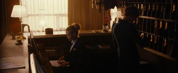Movie still from “The Wave” (2015), directed by Roar Uthaug – A woman sitting at a desk in front of a computer; Medium shot, Over the shoulder angle