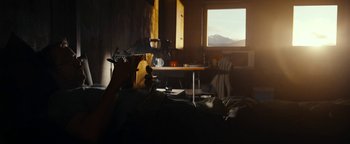 Movie still from “The Wave” (2015), directed by Roar Uthaug – A person sitting on a bed in front of a window; Wide shot, Low angle