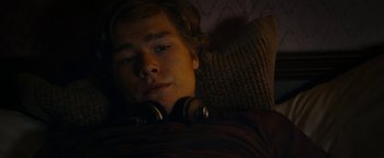 Movie still from “The Wave” (2015), directed by Roar Uthaug – A young man is sleeping in bed with headphones on; Close Up shot, Overhead angle