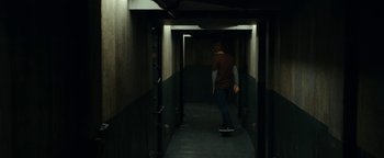 Movie still from “The Wave” (2015), directed by Roar Uthaug – A man riding a skateboard down the side of a hallway; Wide shot, Low angle