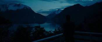 Movie still from “The Wave” (2015), directed by Roar Uthaug – A man standing on a balcony looking at a lake; Extreme Wide shot, High angle
