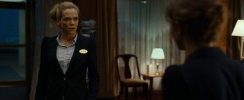 Movie still from “The Wave” (2015), directed by Roar Uthaug – A woman wearing a suit and a badge stands in front of a mirror; Medium shot, Over the shoulder angle