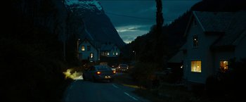 Movie still from “The Wave” (2015), directed by Roar Uthaug – Cars driving down a street at night near a house; Extreme Wide shot, High angle