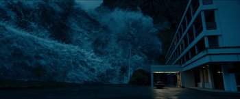 Movie still from “The Wave” (2015), directed by Roar Uthaug – A car parked on the side of the road near a large wave; Extreme Wide shot, High angle