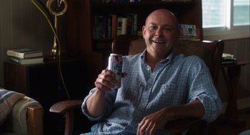 Movie still from “The Way Way Back” (2013), directed by Jim Rash – A man sitting in a chair holding a can of soda; Medium shot, High angle