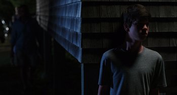 Movie still from “The Way Way Back” (2013), directed by Jim Rash – A young man standing in front of a wooden wall; Medium shot, Low angle