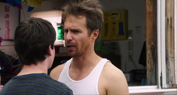 Movie still from “The Way Way Back” (2013), directed by Jim Rash – A man in a white tank top talking to another man; Close Up shot, Over the shoulder angle