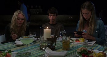 Movie still from “The Way Way Back” (2013), directed by Jim Rash – A man sitting at a dinner table with a candle; Medium shot, Over the shoulder angle