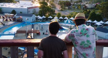 Movie still from “The Way Way Back” (2013), directed by Jim Rash – Two men looking out over a pool from a deck; Medium shot, Over the shoulder angle