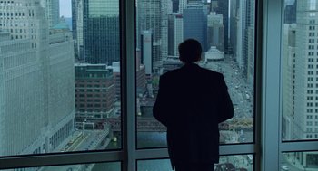 Movie still from “The Weather Man” (2005), directed by Gore Verbinski – A man standing in front of a window looking out at a city; Wide shot, High angle