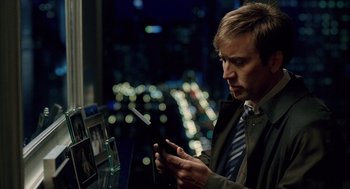 Movie still from “The Weather Man” (2005), directed by Gore Verbinski – A man looking at his cell phone in front of a city skyline at night; Close Up shot, High angle