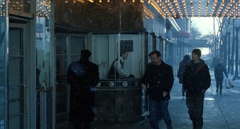 Movie still from “The Weather Man” (2005), directed by Gore Verbinski – A man standing in front of a store on the sidewalk; Wide shot, Over the shoulder angle