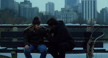 Movie still from “The Weather Man” (2005), directed by Gore Verbinski – Two people sitting on a park bench with a city in the background; Medium shot, Over the shoulder angle
