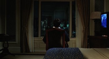 Movie still from “The Weather Man” (2005), directed by Gore Verbinski – A man sitting in a chair looking out a window at night; Wide shot, High angle